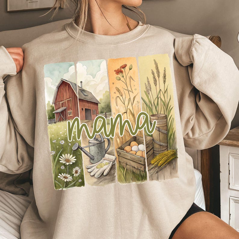 Może przedstawiać: Beżowa bluza z akwarelową ilustracją wiejskiego domu, kwiat&oacute;w, pszenicy i konewki. Tekst "mama" jest napisany zielonym, ozdobnym pismem na przodzie bluzy.