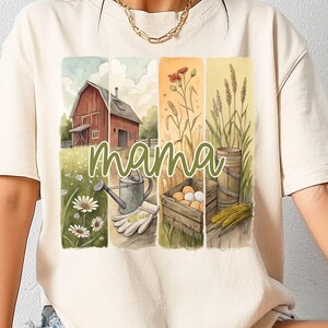 Może przedstawiać: Biały t-shirt z akwarelową ilustracją wiejskiego domu, kwiat&oacute;w, pszenicy, jajek i konewki. Tekst "mama" jest napisany zielonym pismem pośrodku wzoru.
