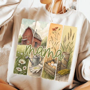 Może przedstawiać: Biała bluza z nadrukiem akwarelowym przedstawiającym czerwony stodołę, kwiaty, pszenicę i słowo "mama".