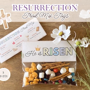 May include: Easter-themed trail mix tags with the words "RESURRECTION Trail Mix Tags" and "He is RISEN." The tags are paired with a clear bag of trail mix, featuring pretzels, goldfish crackers, marshmallows, and candies. A decorative cross and flowers are also present.
