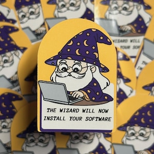 Puede incluir: Una pegatina con un mago de dibujos animados con una larga barba blanca, gafas y un sombrero morado adornado con estrellas y lunas crecientes. El mago está trabajando en un portátil. El texto dice: "THE WIZARD WILL NOW INSTALL YOUR SOFTWARE."