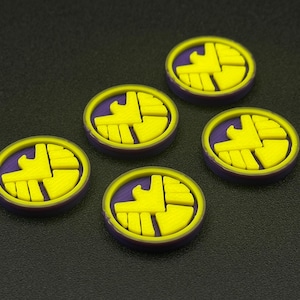 May include: Five purple and yellow round tokens with a stylized eagle design.