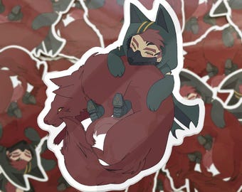 Op de afbeelding: Een gestanste sticker met een gestileerde illustratie van een persoon met roodbruin haar, gekleed in een donkere cape met capuchon en een gezichtsmasker, rustend op de rug van een grote, opgerolde kastanjebruine wolf met gele ogen.