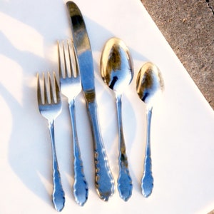 Puede incluir: Un juego de cuatro cubiertos plateados, que incluye un cuchillo para mantequilla, dos tenedores y una cuchara. Los cubiertos tienen un dise&ntilde;o adornado con un patr&oacute;n decorativo.