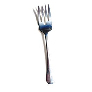 May include: A stainless steel fork with four tines. The fork has a simple, elegant design with a long, slender handle. The tines are evenly spaced and slightly curved. The fork is likely for eating.