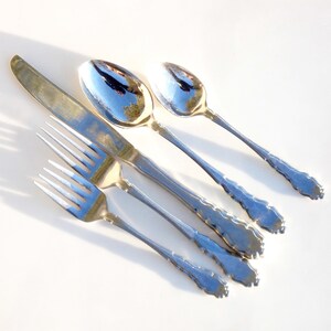 Puede incluir: Un juego de cubiertos de plata, que incluye un cuchillo, un tenedor y dos cucharas. Los cubiertos tienen un dise&ntilde;o adornado con un patr&oacute;n decorativo en los mangos.