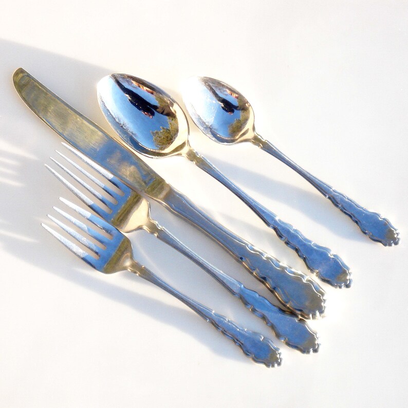 Puede incluir: Un juego de cubiertos de plata, que incluye un cuchillo, un tenedor y dos cucharas. Los cubiertos tienen un dise&ntilde;o adornado con un patr&oacute;n decorativo en los mangos.