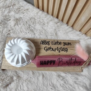 May include: A wooden tray with a white candle holder, a pink candle with the text "Happy Birthday" and the text "Alles Liebe zum Geburtstag".