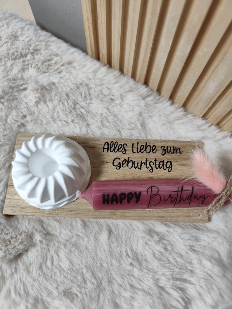 May include: A wooden tray with a white candle holder, a pink candle with the text "Happy Birthday" and the text "Alles Liebe zum Geburtstag".