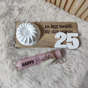 May include: A wooden tray with a white cake mold, white number 25 candles, and a pink candle that says "Happy Birthday". The tray has the text "Ich lass Konfetti f&uuml;r dich regnen" on it.