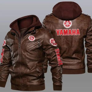 May include: A brown leather jacket with a Yamaha logo on the back and sleeves. The jacket has a zipper closure and a hood.
