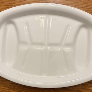 May include: White oval serving platter with three compartments. The platter has blue floral designs on each end. The platter is on a wooden surface.