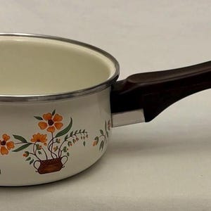 May include: A white ceramic mug with a black handle and the text "But First, Coffee" in a black, bold font. The mug is on a white surface.