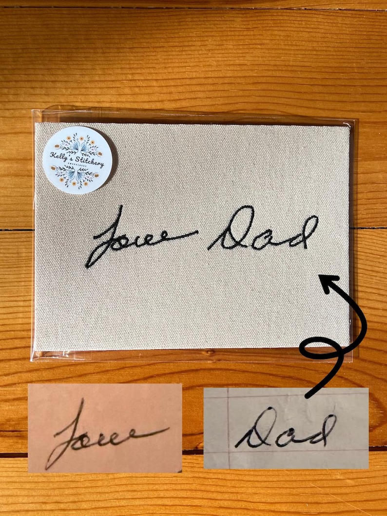 May include: A beige canvas with the embroidered words "Love Dad" in black cursive script. The canvas is in a clear plastic sleeve, with a round sticker in the upper left corner that reads "Kelly's Stitchery". Two smaller images of the handwriting are below.