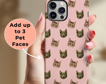 May include: Pink phone case featuring a pattern of cat faces. The case has a camera cutout and the text "Add up to 3 Pet Faces" in a white circle. The case is held in a hand with pink nail polish.
