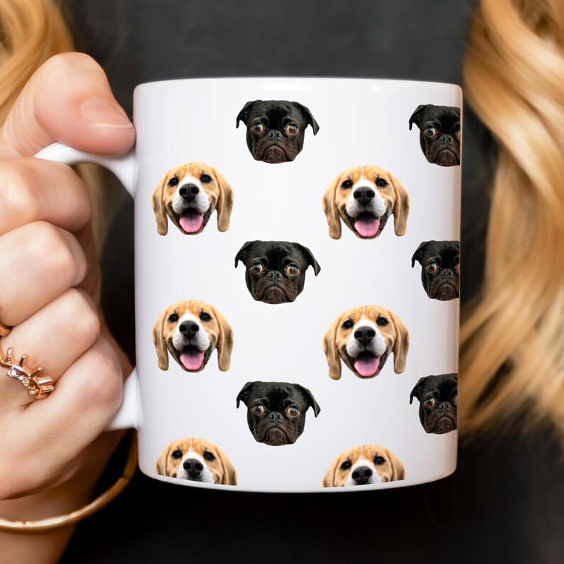 May include: White ceramic mug with a repeating pattern of dog faces. The dogs are a beagle and a pug. The mug has a black handle.