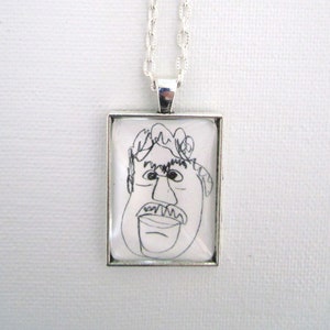 May include: A silver chain necklace with a square pendant featuring a black and white line drawing of a person's face.