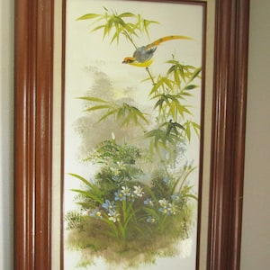 Wall Art
Vintage framed oil painting on canvas with solid wood frame depicting a bird  in a grove of bamboo above pretty blue and white flowers. It is a vintage hand painted decorative item, signed on the lower right corner.