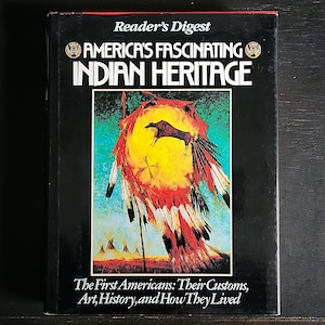 May include: A hardcover book titled "America's Fascinating Indian Heritage" by Reader's Digest. The cover features a colorful illustration of Native American imagery, including a shield, feathers, and a buffalo. The text below reads "The First Americans: Their Customs, Art, History, and How They Lived."