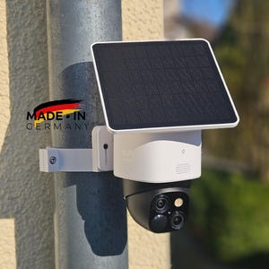 Può includere: Telecamera di sicurezza bianca e nera con pannello solare, montata su un palo di metallo. La telecamera ha una cupola nera e tre lenti. Il pannello solare è quadrato e nero. La parola "eufy" è visibile sulla telecamera.