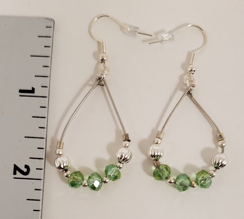 May include: Silver teardrop earrings with green crystal beads and silver beads.