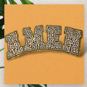 May include: A decorative patch spelling "AMEN" in bold, block letters. The letters have a leopard print pattern with a gold glitter border. The background is a solid orange color.