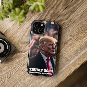 May include: A black phone case with a photo of Donald Trump and the text "TRUMP 2024 MAKE AMERICA GREAT AGAIN".