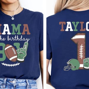 a woman wearing a blue t-shirt with a graphic design featuring a football and the text "MAMA of the birthday BOY" printed on it.