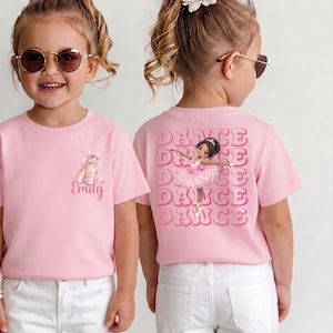 May include: Pink t-shirt with a ballet theme. The front features a graphic of ballet shoes and the name "Emily". The back displays a ballerina graphic with the word "DANCE" repeated multiple times.