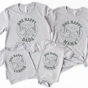 a collection of gray t-shirts with a graphic design featuring a camping scene and the text "One Happy Dada" and "One Happy Mama" printed on them.