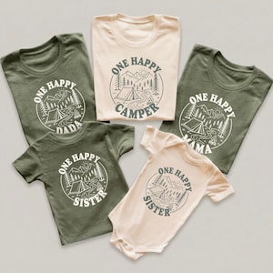 a collection of five t-shirts, each with a unique design and text, arranged in a row.