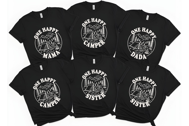 A collection of black t-shirts with white text and graphics, including camping-related designs and phrases such as "One Happy Camper", "One Happy Sister", and "One Happy Mama".