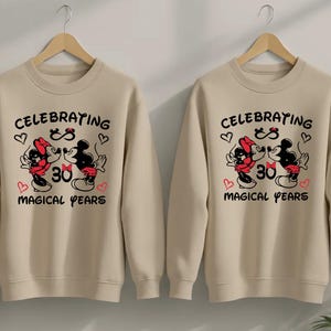Matching Disney couple shirts showcasing Mickey Minnie anniversary artwork with magical years lettering and heart accents. The coordinated outfits create a stylish and heartwarming look for anniversary dinners, Disneyland visits, or romantic photos.