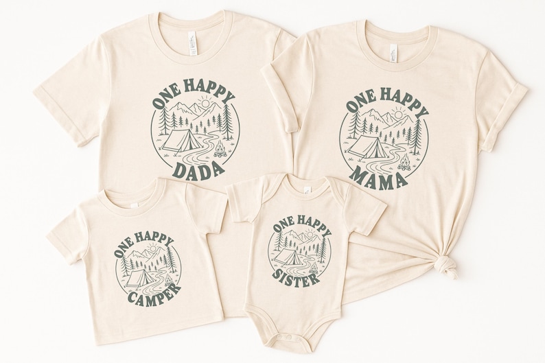 a collection of four beige t-shirts with a graphic design featuring camping and nature elements, along with the text "One Happy Dada" and "One Happy Mama" printed on them.