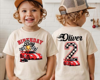 May include: A beige short-sleeve t-shirt featuring a red race car, a gold trophy, and the text Birthday Boy on the front. The back displays the name Oliver in a flame font above a large number 2 with a checkered pattern and a red race car graphic.