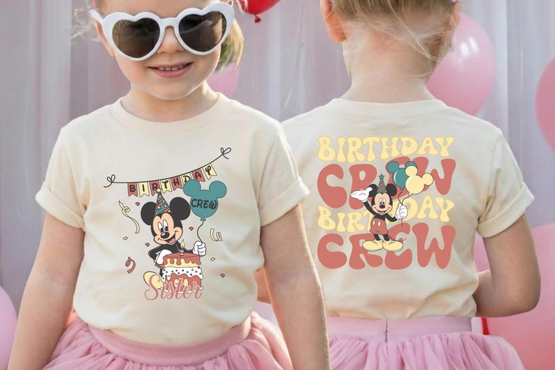 A young girl wearing a white t-shirt with a Mickey Mouse design and sunglasses, smiling at the camera.