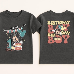 two black t-shirts with a Mickey Mouse design and text related to a birthday celebration.