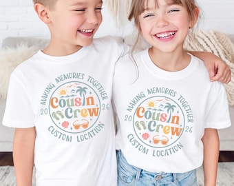 May include: White short-sleeve t-shirts featuring a circular graphic with the text "Making Memories Together," "Cousin Crew," "2026," and "Custom Location." The design includes illustrations of a sun, palm tree, flip-flops, shell, and sunglasses.