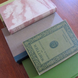 K&ouml;nnte beinhalten: Ein Stapel von vier B&uuml;chern mit gr&uuml;nen, braunen und cremefarbenen Einb&auml;nden. Das oberste Buch hat ein goldfarbenes Design und den Text "WHITTIER" und "GEORGE R. CARPENTER" auf dem vorderen Einband. Der Text "POULAR RIVERSIDE" und "LIBRARY" ist ebenfalls auf dem Einband zu sehen.