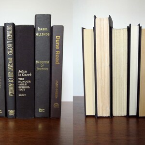 May include: A set of six black hardback books with gold lettering on the spines. The books are arranged in a vertical stack. The titles of the books are "American Icon", "The Giant Rat of Sumatra", "John le Carre The Honourable Schoolboy", "Daughter of Fortune", "Dune Road", and "The Giant Rat of Sumatra".