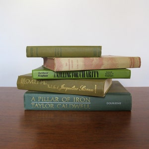 K&ouml;nnte beinhalten: Ein Stapel von sechs alten gebundenen B&uuml;chern mit gr&uuml;nen und braunen Einb&auml;nden. Das oberste Buch tr&auml;gt den Titel "A Killing for Charity" und das unterste Buch den Titel "A Pillar of Iron, Taylor Caldwell, Doubleday".