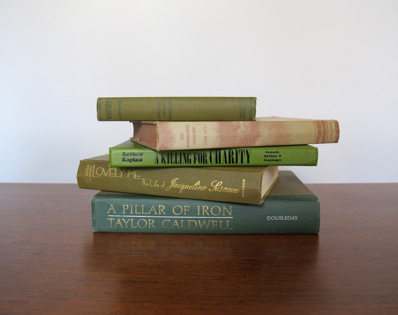 K&ouml;nnte beinhalten: Ein Stapel von sechs alten gebundenen B&uuml;chern mit gr&uuml;nen und braunen Einb&auml;nden. Das oberste Buch tr&auml;gt den Titel "A Killing for Charity" und das unterste Buch den Titel "A Pillar of Iron, Taylor Caldwell, Doubleday".