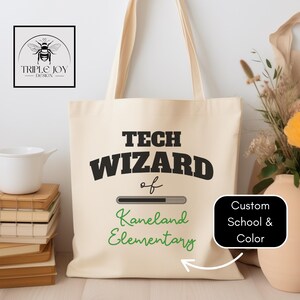 May include: Cream tote bag with the words "TECH WIZARD" in black, "of Kaneland Elementary" in green, and a loading bar graphic. The bag also features a logo with a bee design.