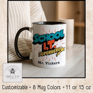 May include: White ceramic mug with a black handle and rim. The mug features the text "SCHOOL I.T. SUPERHERO" in teal and orange, with a yellow star. The name "Mr. Vickers" is printed below the text. The mug is customizable and available in 11 or 15 oz sizes.