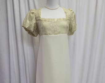 May include: A light green empire waist gown with a square neckline and short, puffed sleeves. The bodice features embroidered floral details, and the long skirt is a solid, flowing fabric. A pearl necklace is around the neckline.