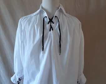 May include: A white long-sleeved shirt with a lace-up neckline and black ribbon ties. The shirt has gathered sleeves and a relaxed fit.