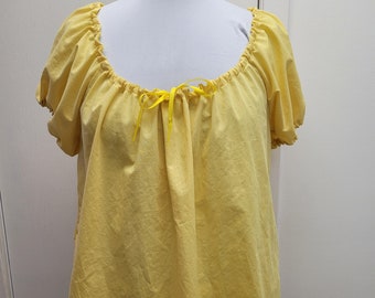 May include: A yellow peasant top with a gathered neckline and short sleeves. The top has a yellow ribbon tied at the neckline.
