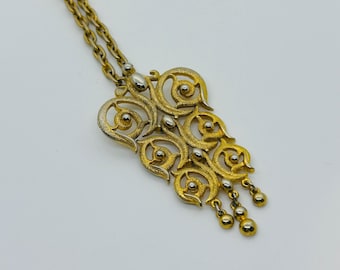 Collar con colgante articulado de pergamino texturizado en tono dorado, estilo vintage.