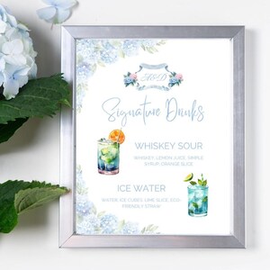May include: A white sign with blue watercolor flowers and the text "A&D Signature Drinks" at the top. The sign lists two drinks: "Whiskey Sour" with a watercolor illustration of a whiskey sour and "Ice Water" with a watercolor illustration of a glass of ice water.