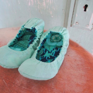 May include: Two pairs of light blue fabric ballet flats with a floral print lining.